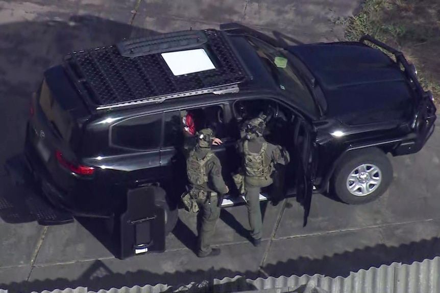 Officers dressed in camo outside a house