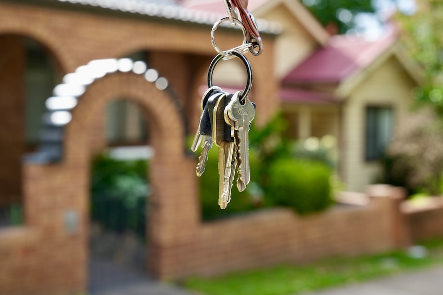 A set of house keys with houses in the background.