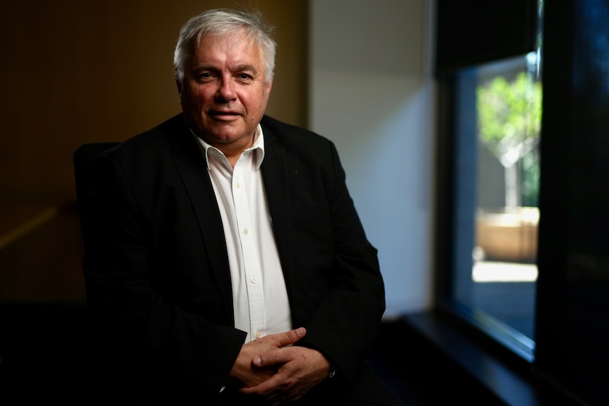 Rex Patrick wearing a black suit sitting near a window.