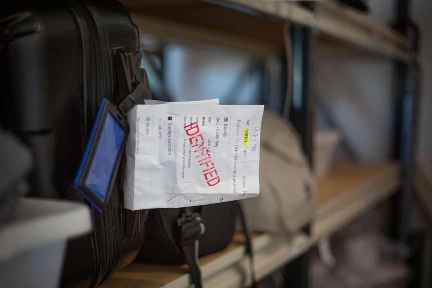 A ticket with the words Identified stamped on it on a suitcase handle.