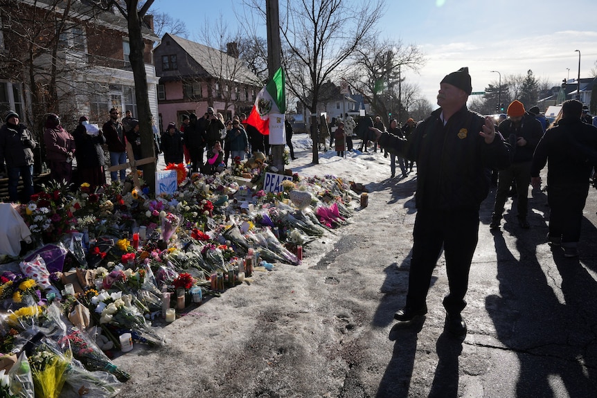 flowers line a street as a police officer speaks to people 