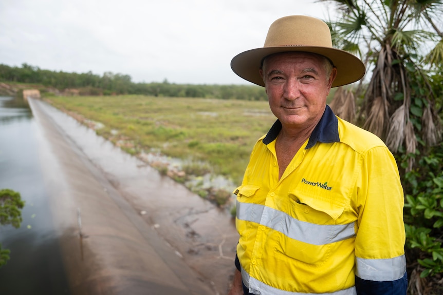 A man in a yellow high-vis shirt stands near a spillway