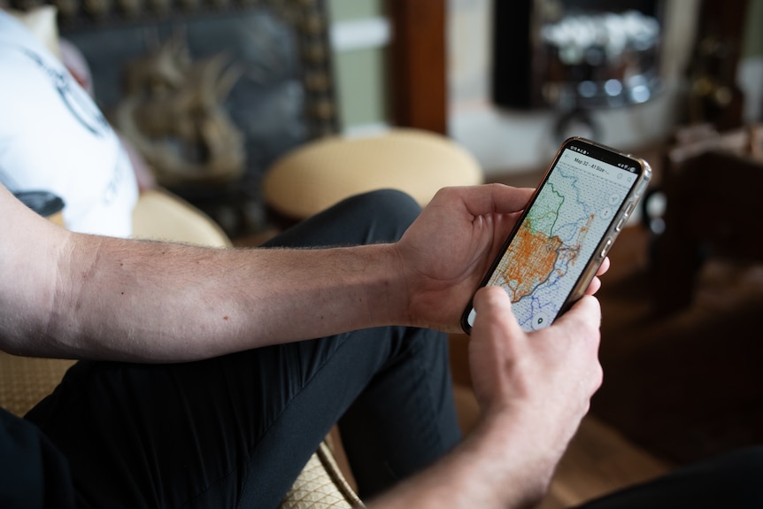 Smart phone in mans hands, with map on screen.