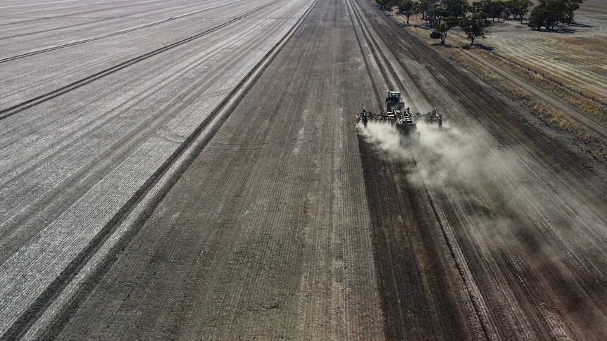 A drone image of a dry sowing machine sparking a massive dust cloud on a brown paddock