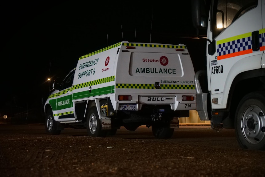An ambulance and police truck on the road at night.