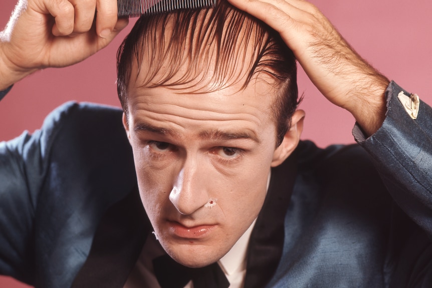 Garry McDonald as Norman Gunston, combing his hair.