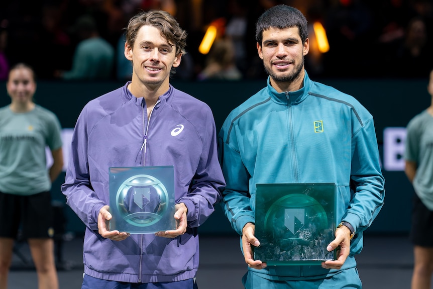 Alex de Minaur and Carlos Alcaraz at a trophy presentation after a tennis match.