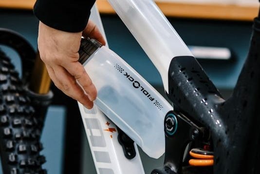 hand holding a water bottle being placed into a bike frame