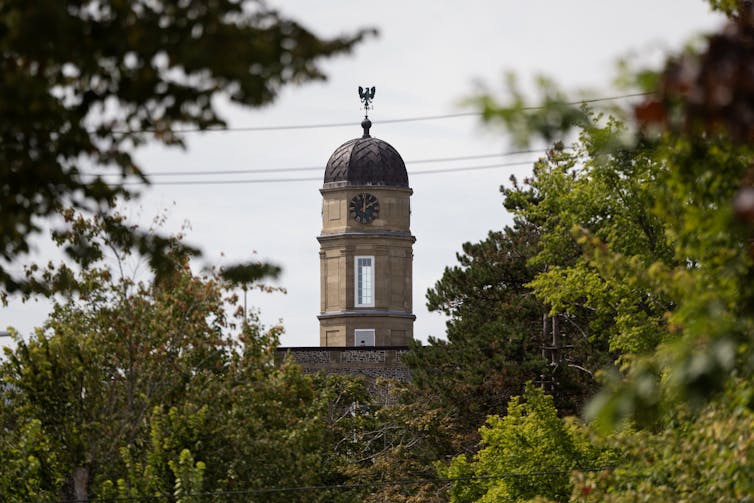 A clock tower seen atop a stone building.