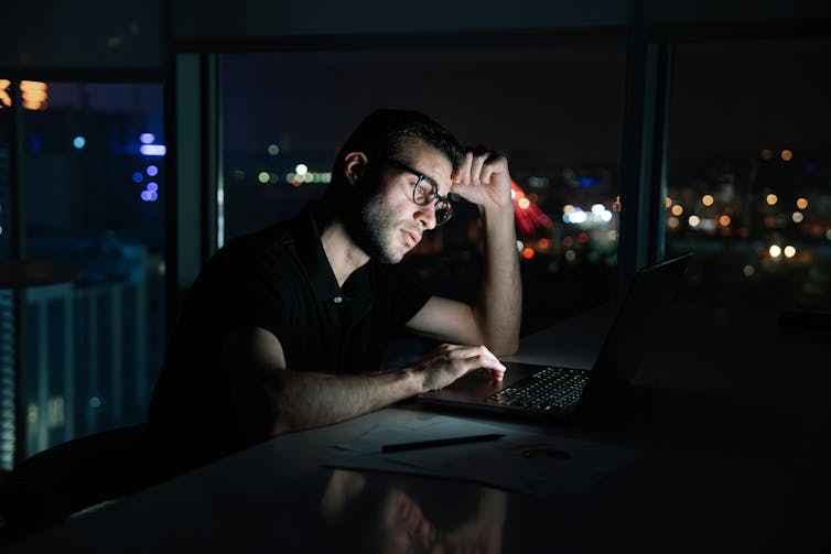 A man sitting at this desk in front of his computer.