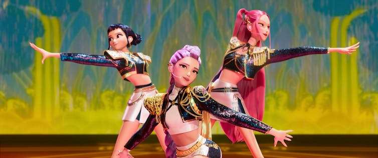 Three animated female performers extending their hands on a stage.
