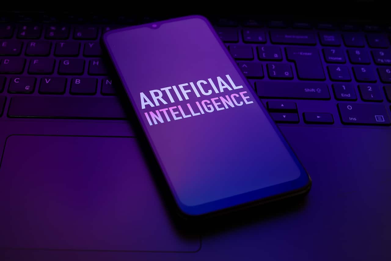A phone screen displaying the words Artificial Intelligence is lying on a keyboard.