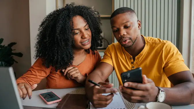 Couple discussing saving money and financial planning in front of a laptop with a calculator and notebook