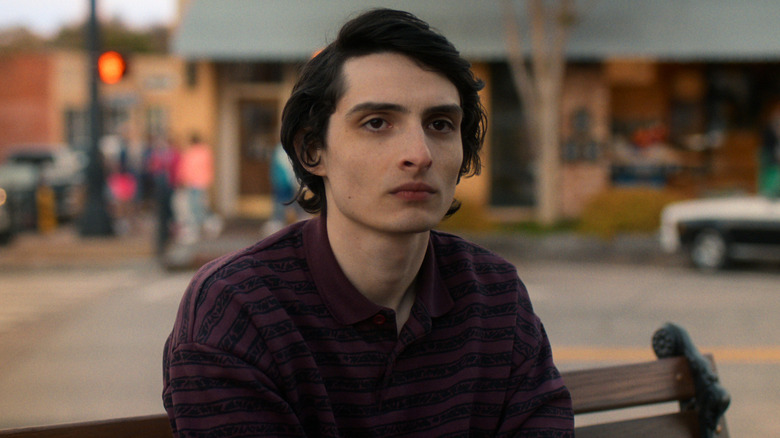 Mike Wheeler sitting somberly on a bench by the Hawkins earthquake memorial in the 