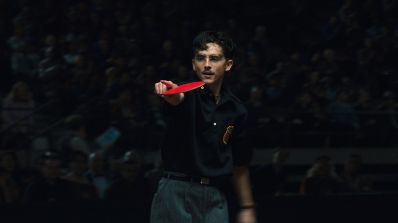 Timothée Chalamet as Marty Mauser pointing while holding a ping pong paddle in Marty Supreme