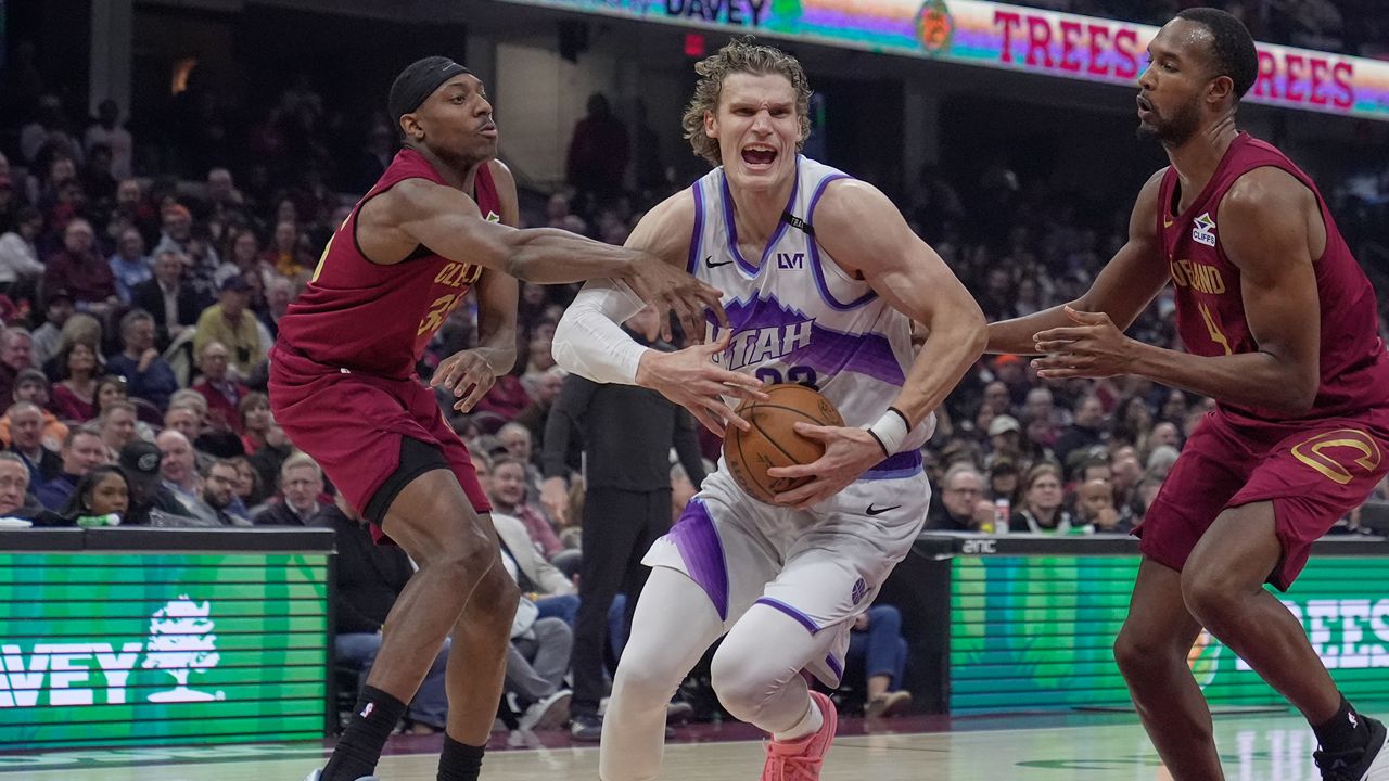 Utah Jazz forward Lauri Markkanen, center, drives between Cleveland Cavaliers forward Nae'qwan Tomlin, left, and center Evan Mobley, right, in the first half of an NBA basketball game in Cleveland, Monday, Jan. 12, 2026. (AP Photo/Sue Ogrocki)