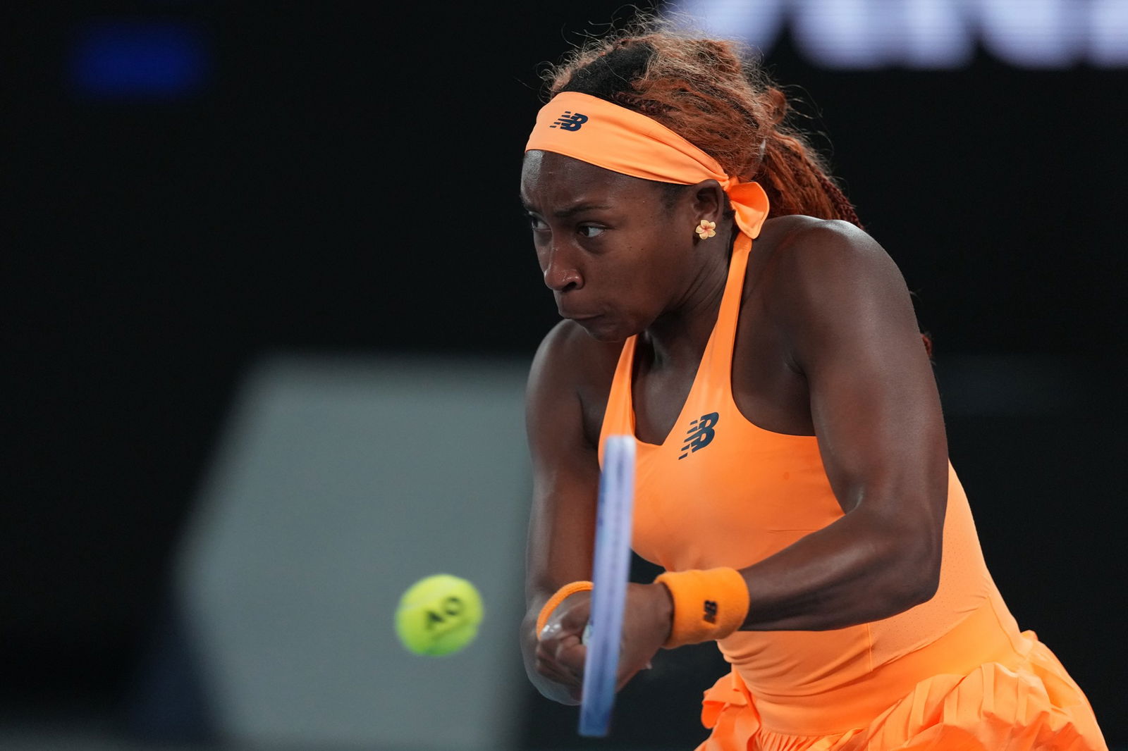 coco gauff hits a backhand while wearing orange tennis suit
