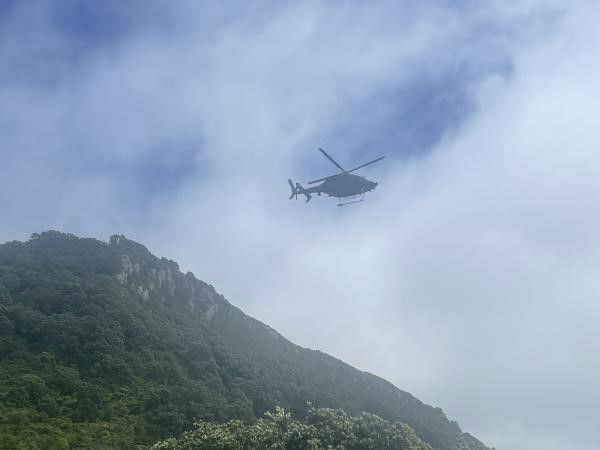 A helicopter flies near grassy cliffs