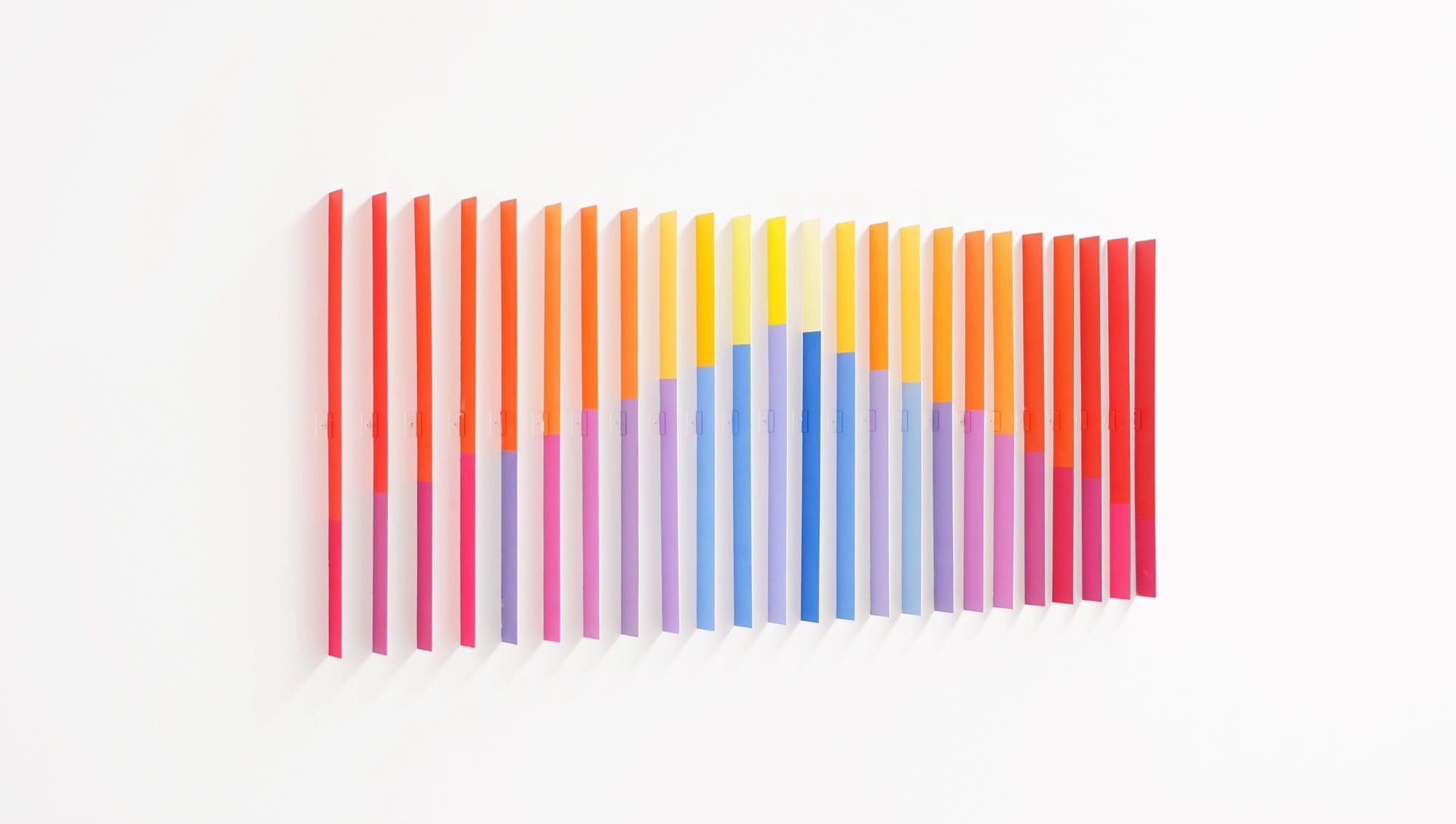 an installation by Luftwerk of a vibrant gradient of thin, vertical strips on a gallery wall