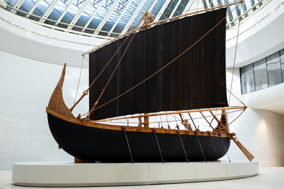 Magan Boat - ancient wooden ship with large black sail displayed in a modern white gallery at Zayed National Museum