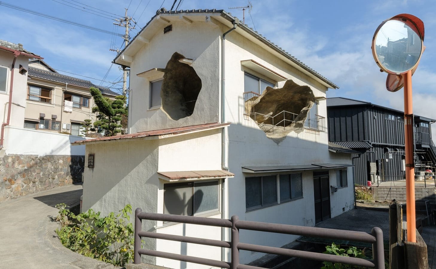 An art installation comprising a small house with holes in it that open to what looks like a cave on the inside