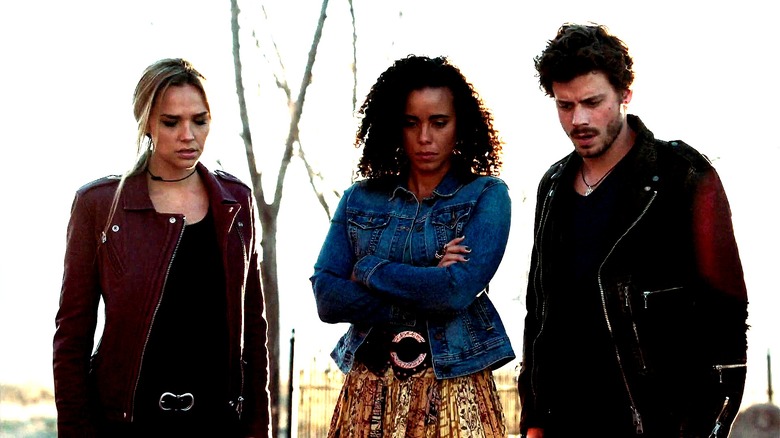 Olivia,  Fiji, and Manfred stand outside, looking down