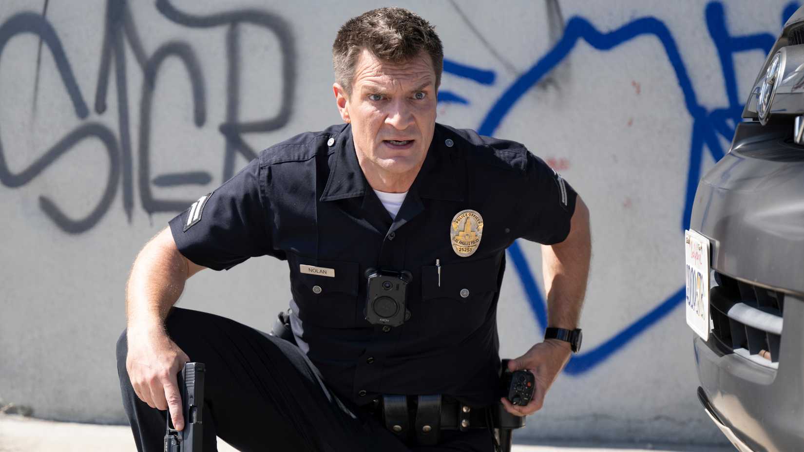 Nathan Fillion as John Nolan kneeling and looking shocked in The Rookie