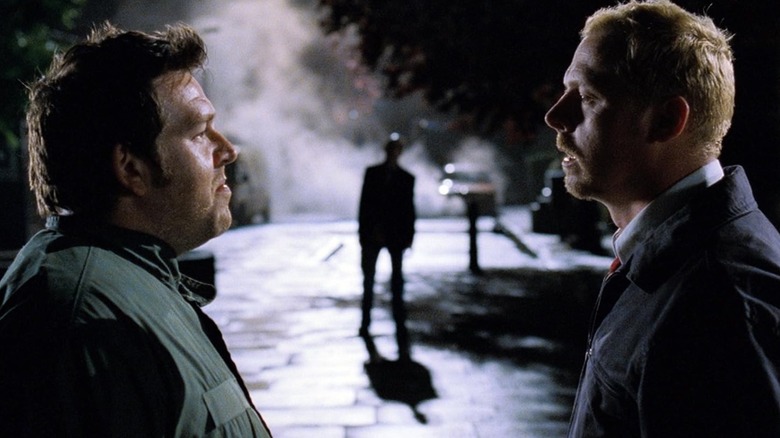 Ed (Nick Frost) and Shaun (Simon Pegg) looking at each other while a figure stands in the background in 