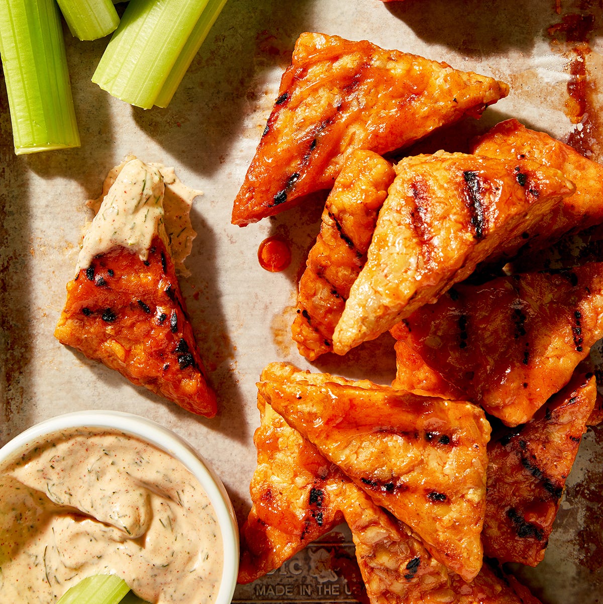 triangle shaped tempeh buffalo wings with a dill chipotle mayo and celery