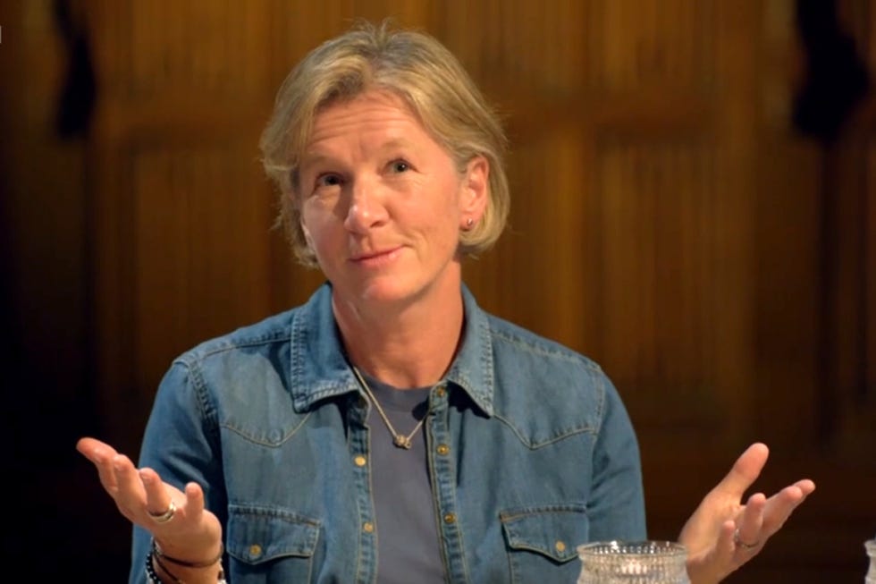 person gesturing while seated at a table