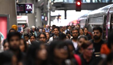 People walking along a busy train platform in a large city.