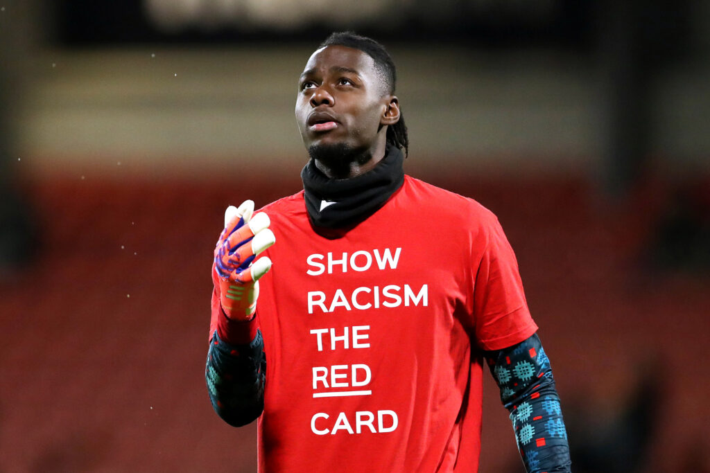 WREXHAM, WALES - OCTOBER 28: Arthur Okonkwo of Wrexham warms up wearing a shirt which reads 'Show Racism The Red Card' prior to the Carabao Cup Fourth Round match between Wrexham and Cardiff City at Racecourse Ground on October 28, 2025 in Wrexham, Wales. (Photo by Charlotte Tattersall/Getty Images)