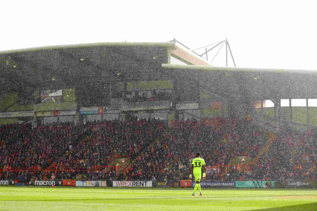 WREXHAM, WALES - MARCH 29: Arthur Okonkwo of Wrexham looks on in the rain during the Sky Bet League Two match between Wrexham and Mansfield Town at Racecourse Ground on March 29, 2024 in Wrexham, Wales. (Photo by Jan Kruger/Getty Images)