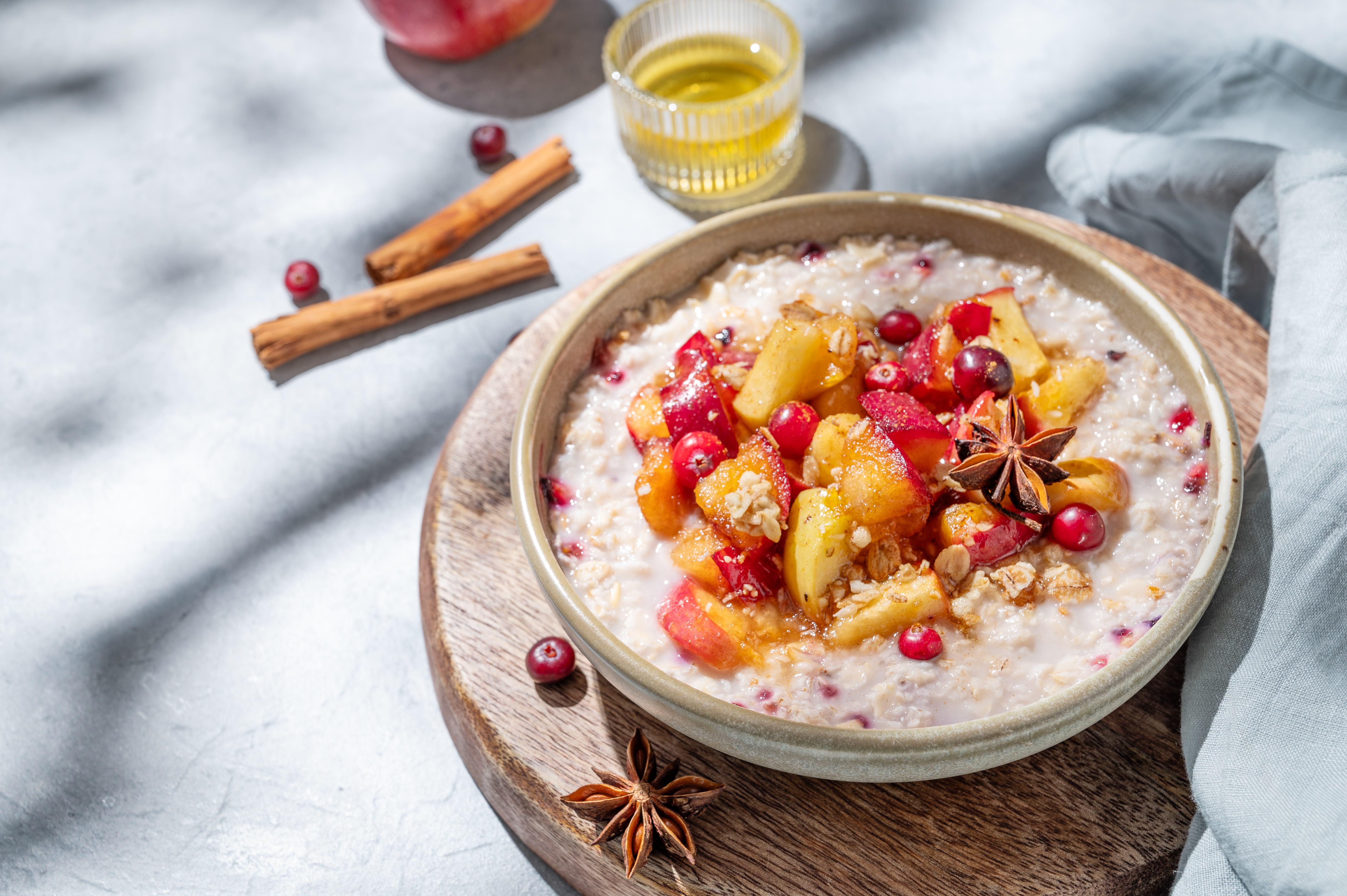 Overnight oatmeal with apple, cranberry and cinnamon in a bowl on a wooden board.