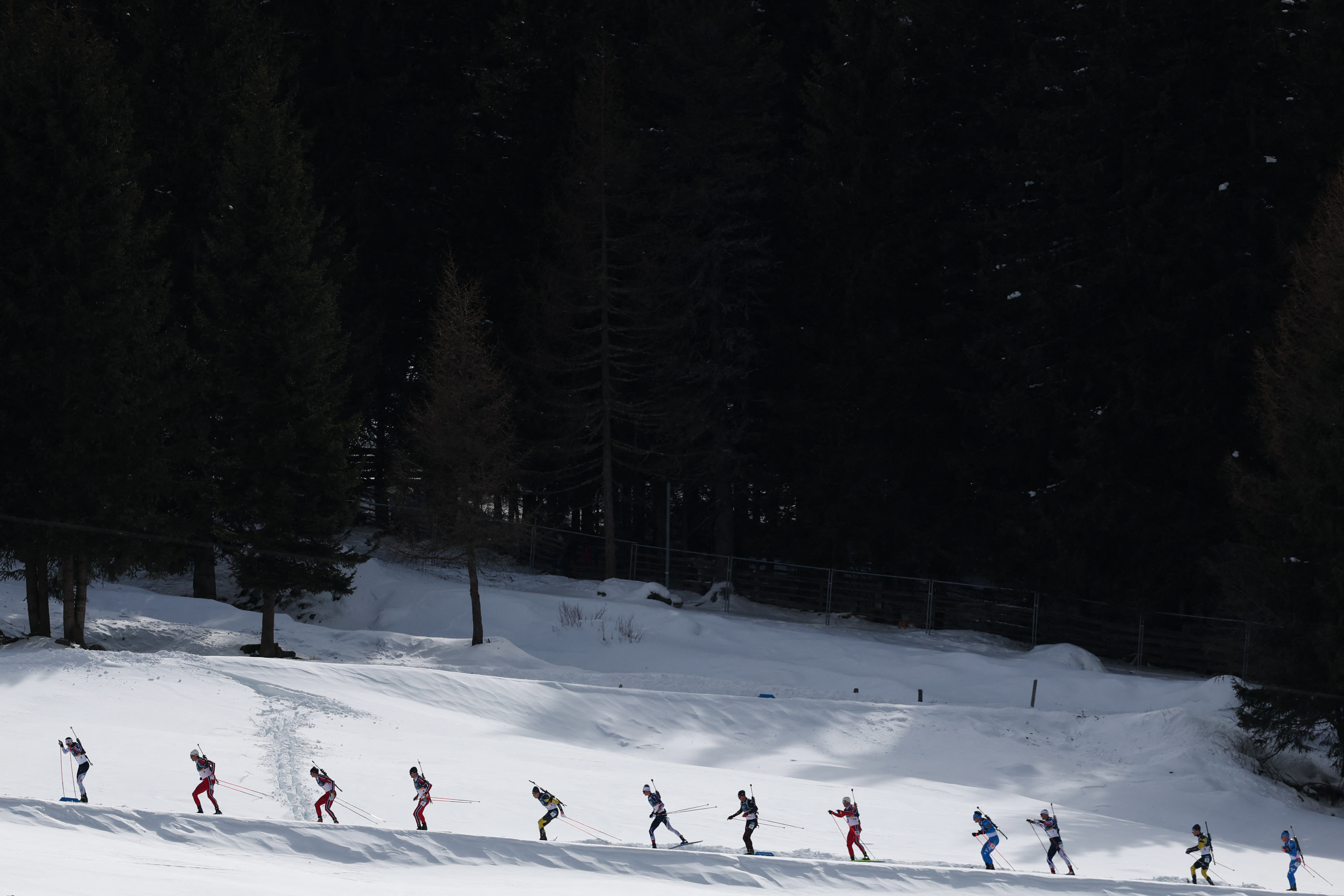 Biathletes skiing during the men's 15km mass start event at the Milano Cortina 2026 Winter Olympic Games.