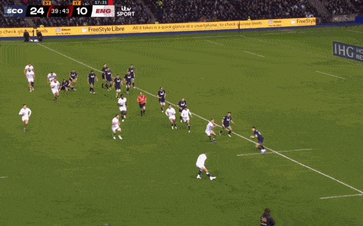 A player in a dark uniform kicking a rugby ball during a match between Scotland and England, with the score showing Scotland 24, England 10.