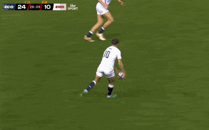A rugby player in a white jersey with the number 10 prepares to kick the ball.