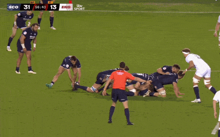 Rugby players forming a scrum with a referee watching, score SCO 31 - ENG 13.
