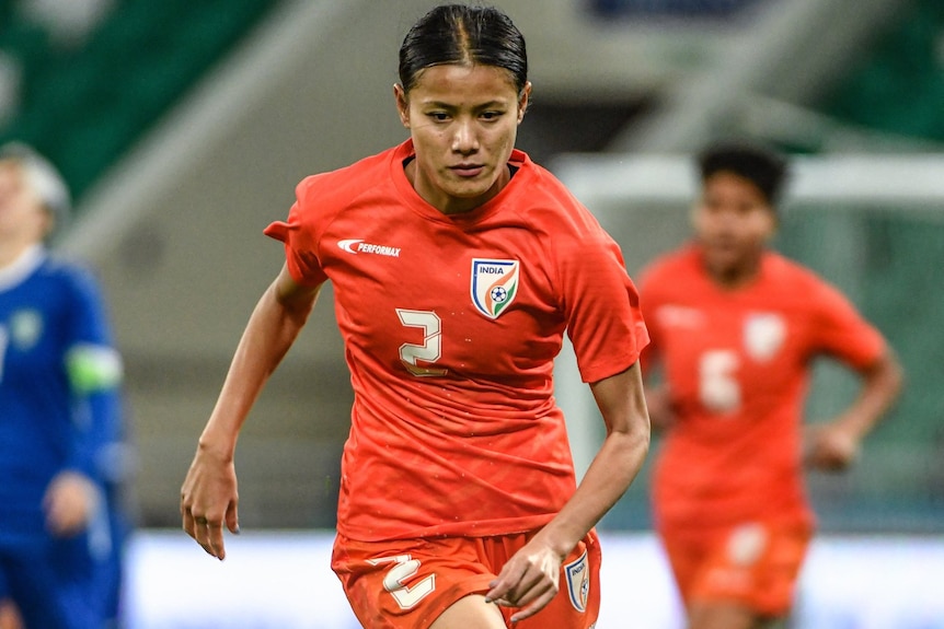 Woman soccer player runs with ball at feet