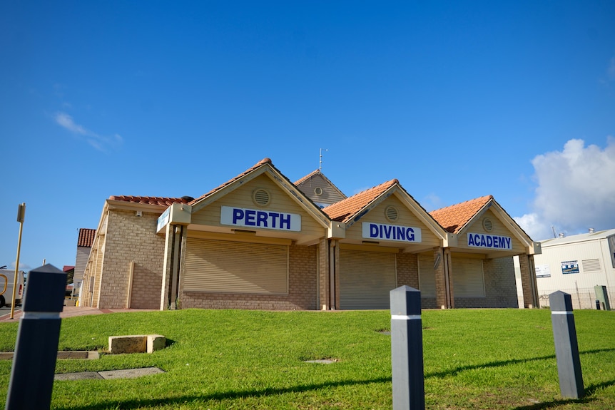 A yellow brick building with the words 'Perth', 'Diving' and 'Academy' written on signs.