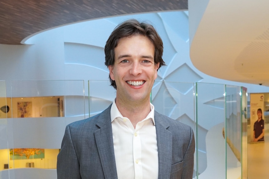 A man in a grey suit standing in a hospital.