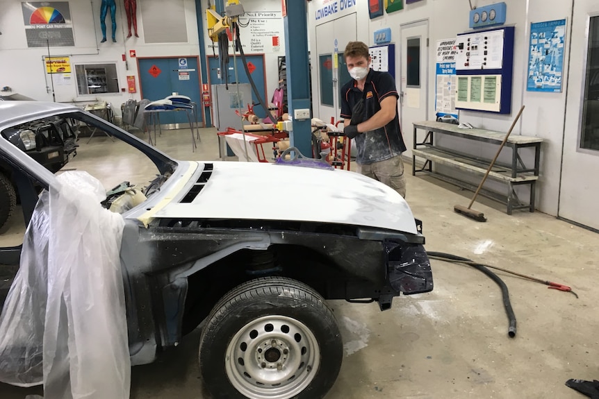 guy in mask spraying car