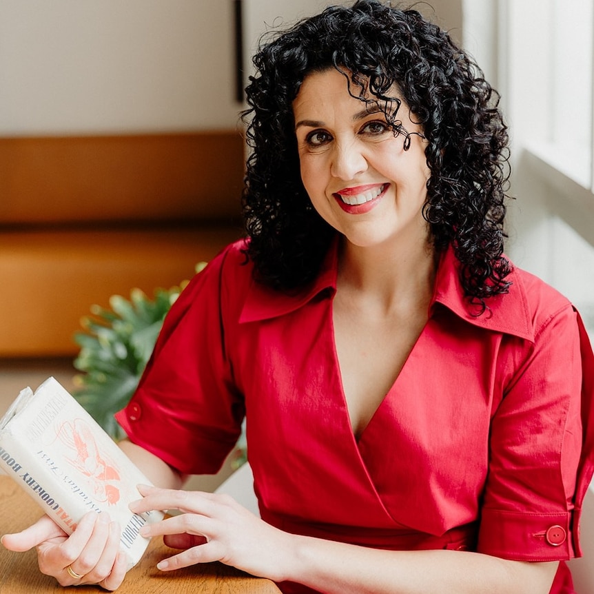 Woman with long, curly, brown hair wears a red outfit.