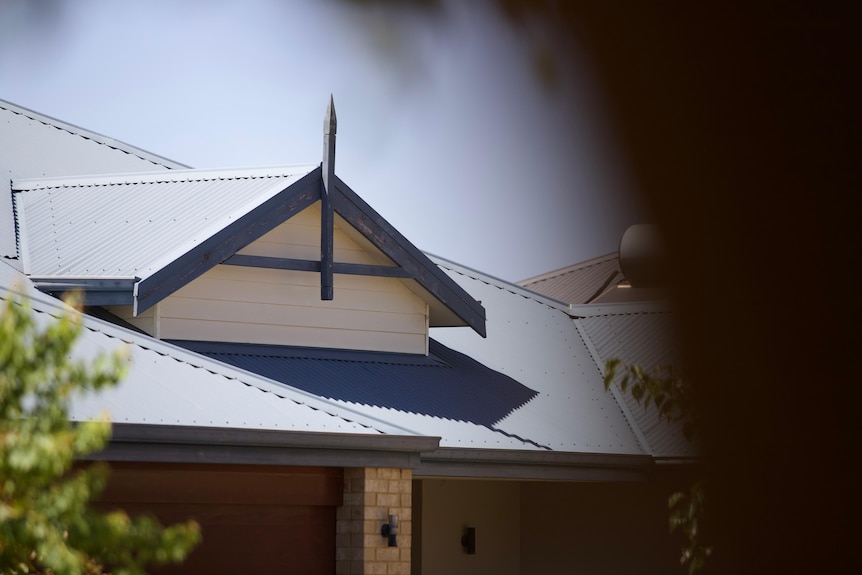A close-up shot of the roof of an unidentified house in the suburbs of Perth, with trees in the foreground.