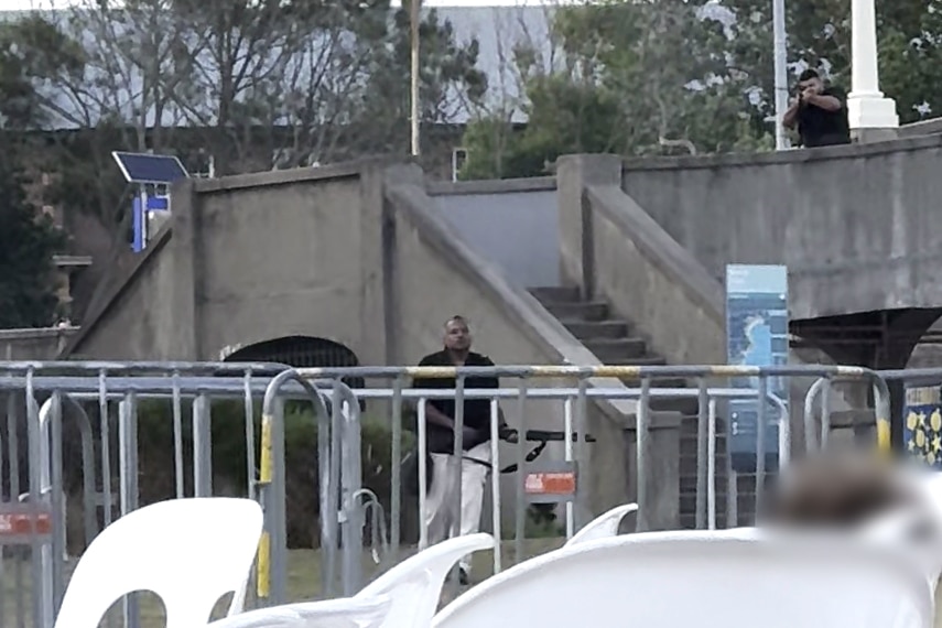 Two men with guns by a footbridge during the terrorist attack at Bondi Beach. 