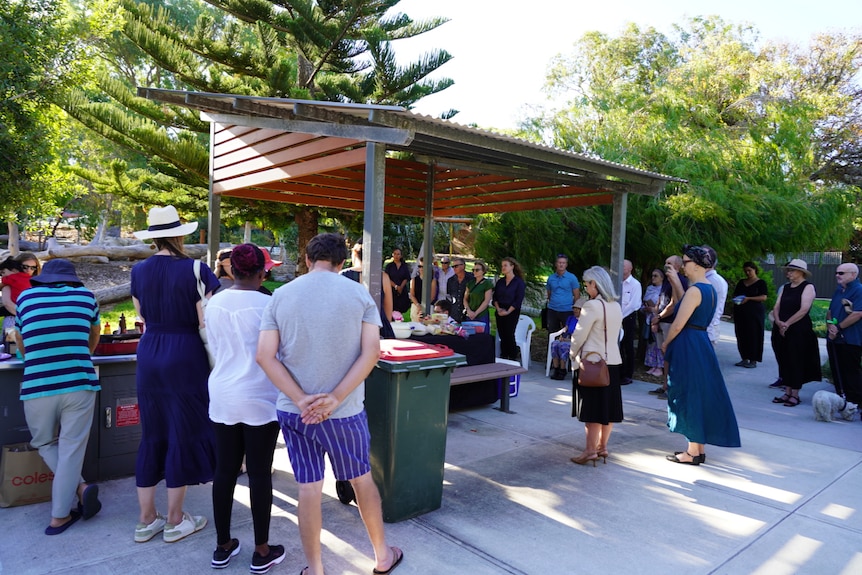 A group of people pause for a minute's silence.  