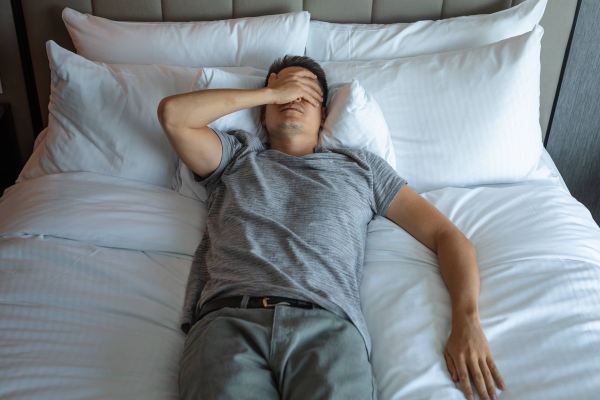 Stressed exhausted man lying in bed.