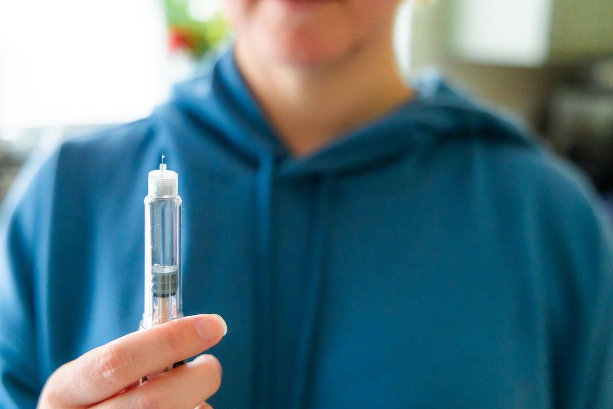 Close up of a woman's hands holding an injection pen