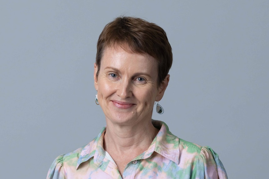 A woman in a pastel coloured shirt smiling at the camera