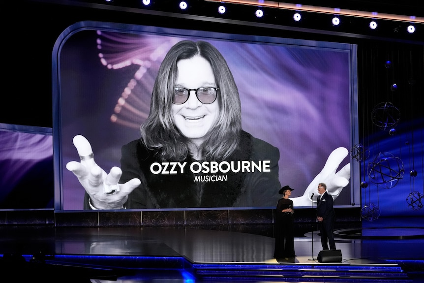 A large screen on stage with an image of Ozzy Osbourne displayed on it.